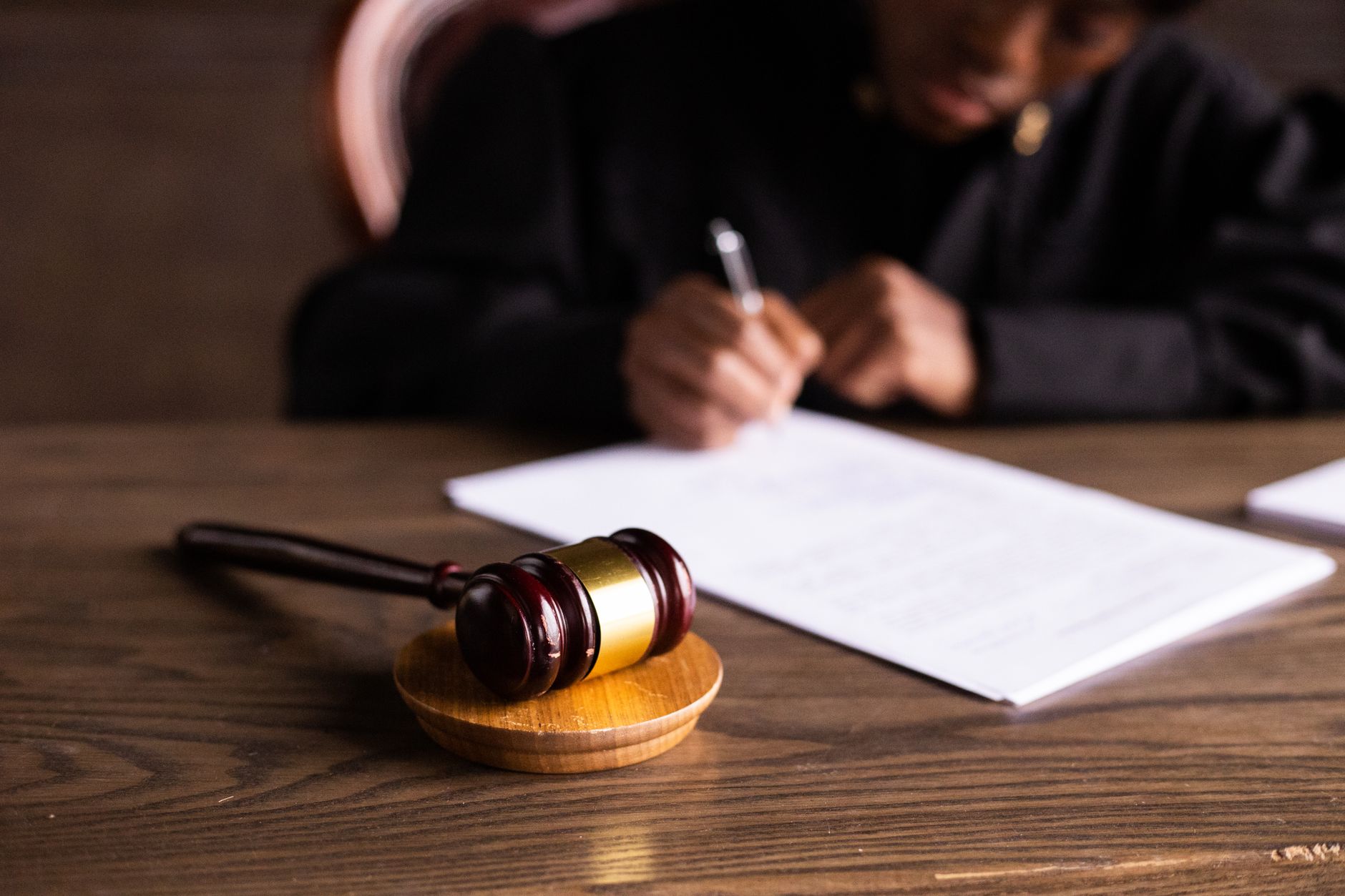A judge signing court documents next to a gavel